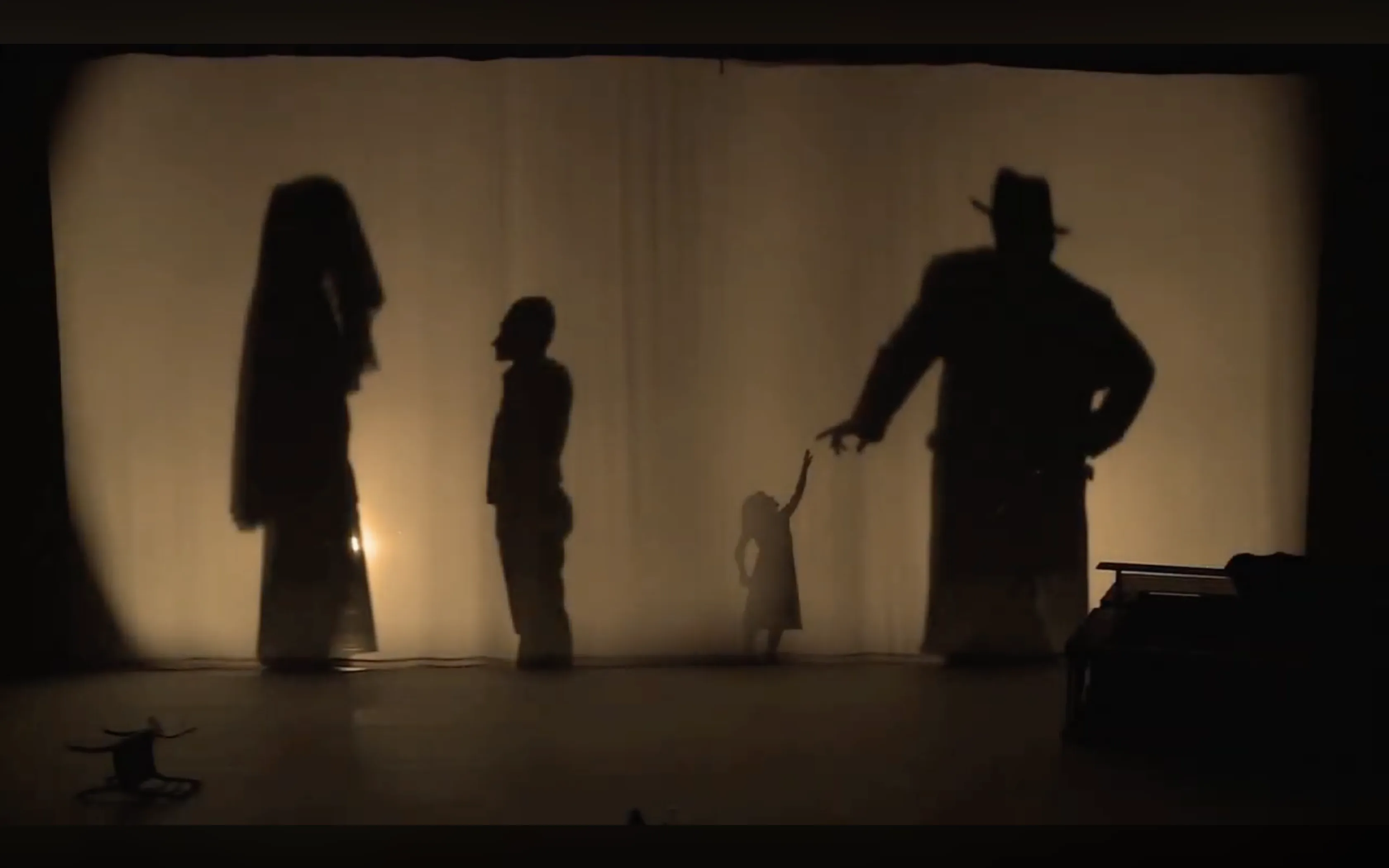 The Characters as silhouettes behind the curtain